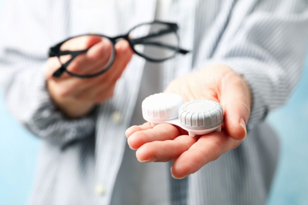 Soczewki i okulary korekcyjne pokazywane na dłoniach